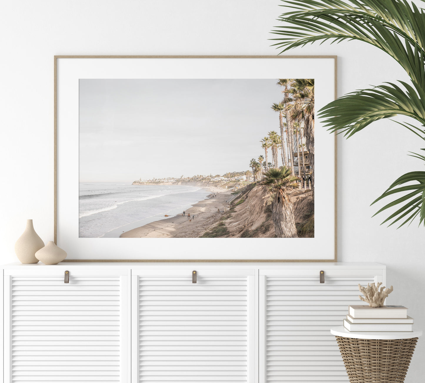 Horizontal, California coast print featuring a high vantage point overlooking Pacific Beach, with tall palm trees, a sandy beach, and the ocean. This coastal print offers a beautiful seascape. Photograph in minimalist mock up.