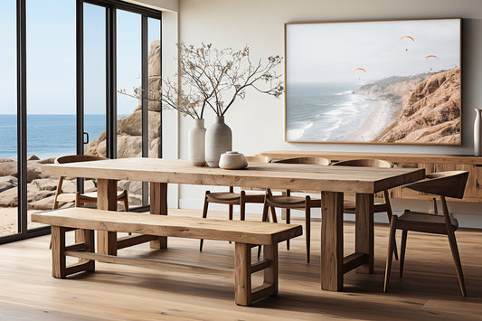 Fine art of Torrey Pines, San Diego California horizontal print of hazy high-angle landscape beach photography captures a light blue ocean meeting a sandy beach with many beach goers. To the right, tall tan and brown cliffs rise as iconic coastal scenery. Four white paragliders gliding in the pale pastel sky, a travel photography moment. The scene emphasizes the cliffs, beach, and the paragliders' presence in the expansive large beach art view. Photograph in dining room minimalist mock up.