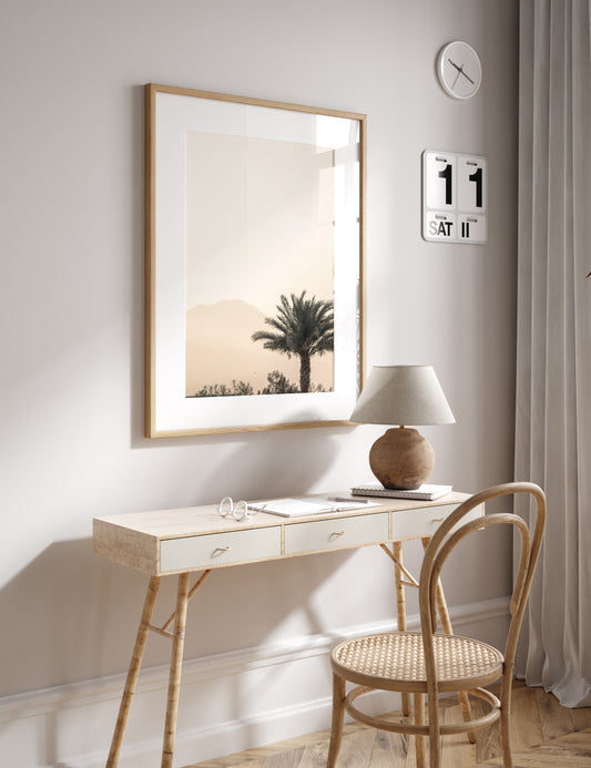 Vertical coastal print of a single palm tree silhouetted against a hazy sky with a distant mountain range, creating a calm beach print feel. Photograph in minimalist mock up.