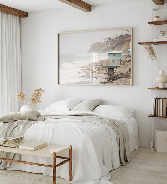 A serene piece of beach photography showcasing a light blue lifeguard tower, number 5, on the San Diego coast. This pastel beach art captures the iconic tower standing on wet sand with gentle ocean waves receding, under a hazy, overcast sky with distant cliffs. A perfect landscape lifeguard tower print for coastal theme wall art. Photograph in minimalist surf art mock up.