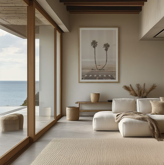 Vertical coastal photography of two leaning palm trees on a hazy Oceanside beach, with ocean waves in the background and a crosswalk in the foreground. Photograph in minimalist mock up.