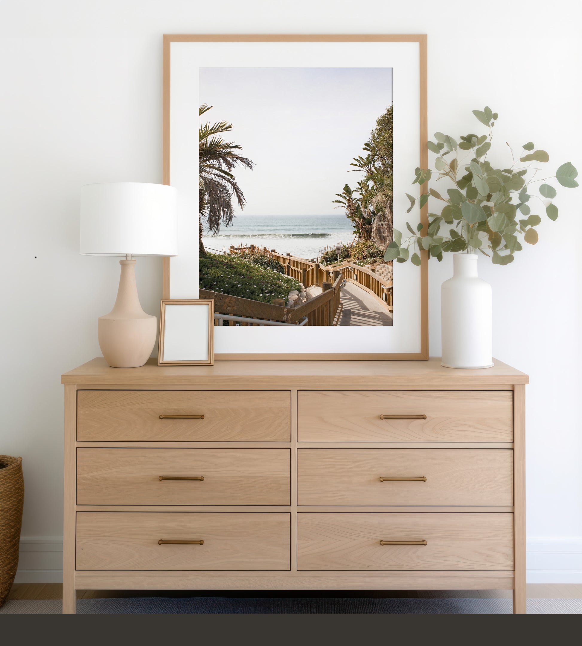 Vertical coastal wall print featuring a stairway leading down to a beach with palm trees and ocean view. Photograph in minimalist mock up.