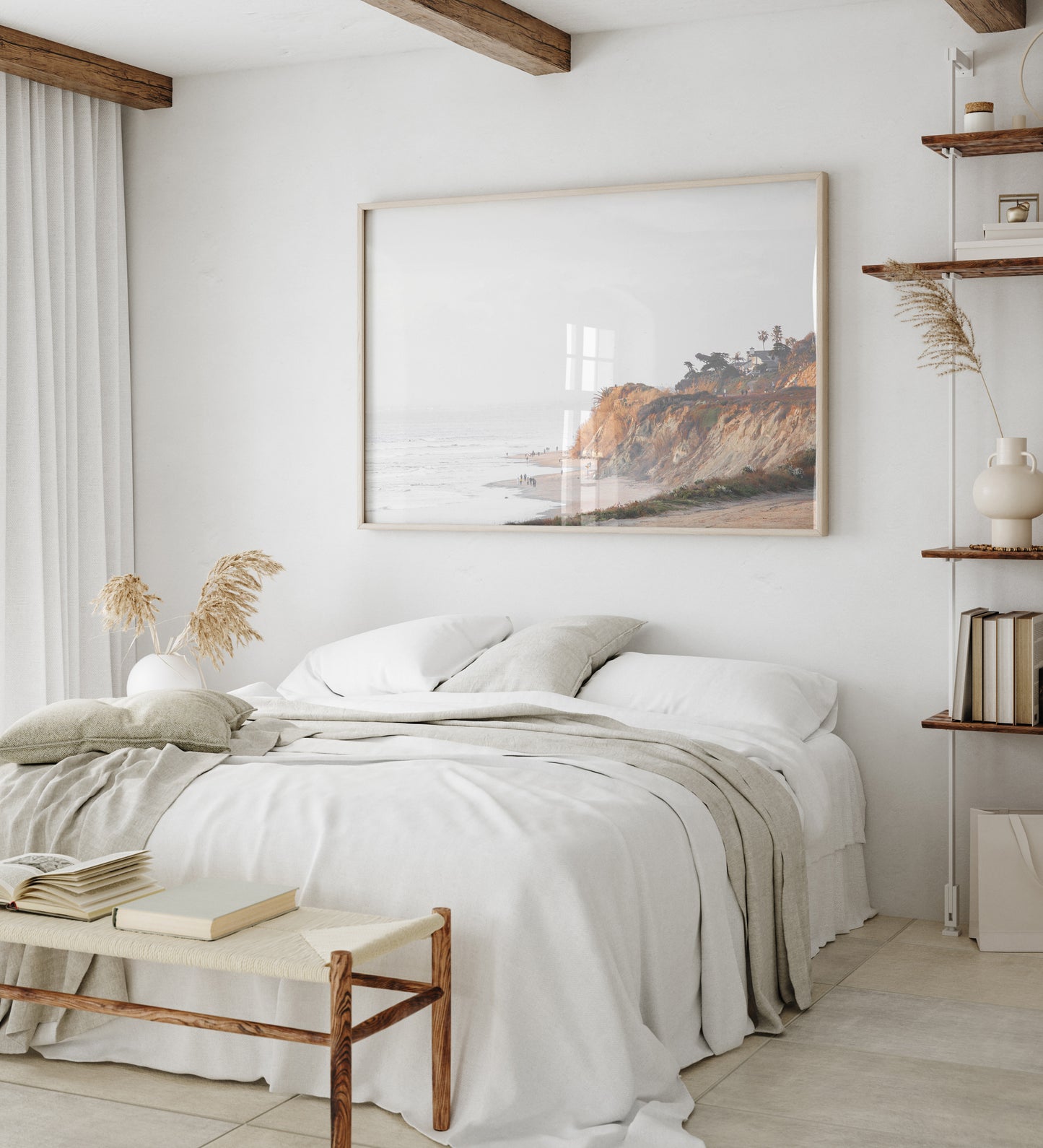 Fine art of Torrey Pines, San Diego California horizontal print of hazy high-angle landscape beach photography captures a light blue ocean meeting a sandy beach with many beach goers. To the right, tall tan and brown cliffs rise as iconic coastal scenery. Photograph in minimalist framed bedroom mock up.