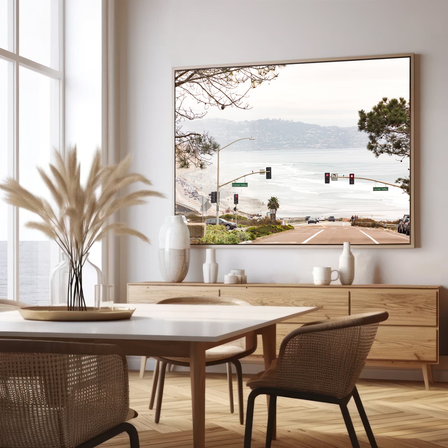 A hazy eye-level shot of San Diego Streets looks down a sloping road featuring red traffic lights and "Carmel Valley" signs, capturing a Local Surf Print vibe. The foreground of this California Wall Art showcases landscape and cars, framed by tree branches at the top, adding to the San Diego Photo aesthetic. The lighting suggests a hazy daytime, perfect for Minimalist Beach Wall Art. This horizontal San Diego print makes a great piece of horizontal beach wall decor. Photograph in minimalist dining mock up
