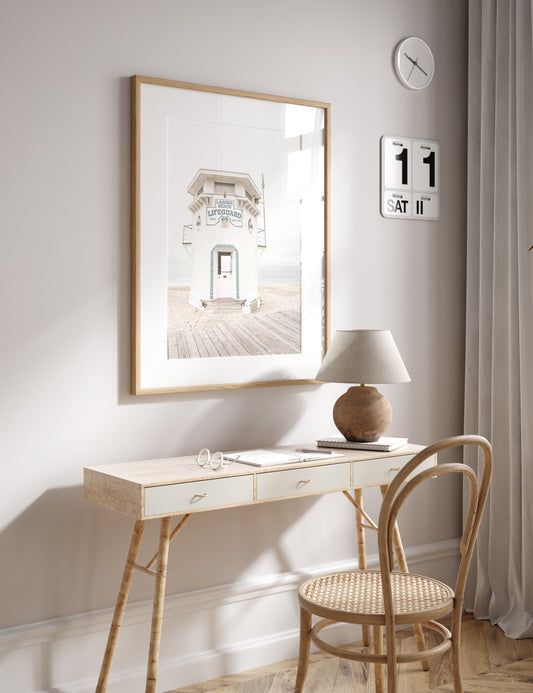 Vertical coastal photography of a white lifeguard tower at Laguna Beach, California, with a clear blue sky and ocean in the background. This neutral ocean print highlights coastal architecture. Photograph in minimalist mock up.
