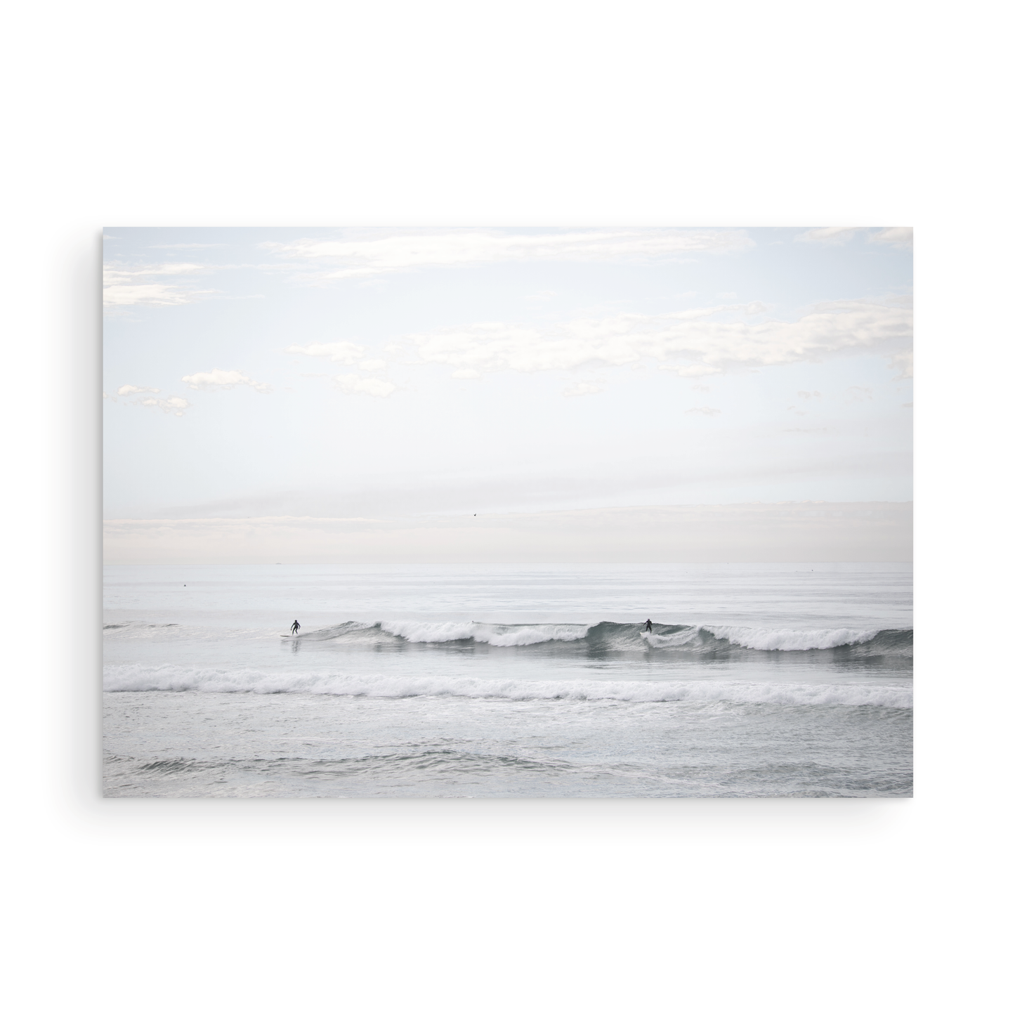 Horizontal minimalist ocean art with a close-up blue waves print of water, featuring subtle ripples and soft textures, ideal as a neutral ocean print, surfers in the waves. Photograph in minimalist mock up.