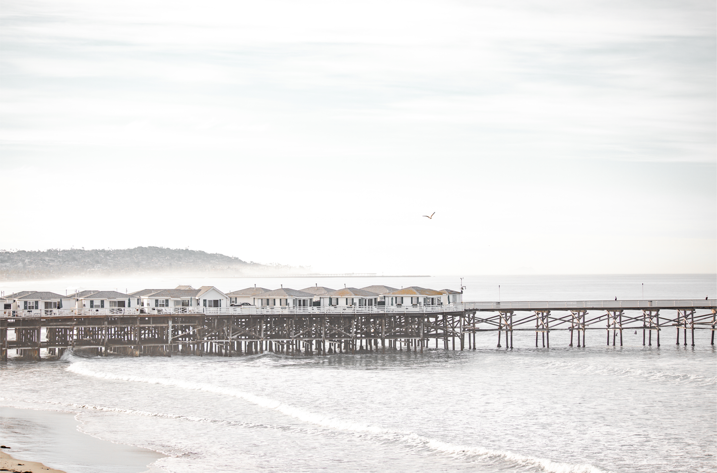 Landscape coastal photography of Crystal Pier in Pacific Beach, San Diego, extending into the calm ocean with gentle waves.