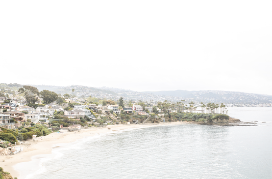Horizontal coastal photography featuring a beach scene with a calm ocean and beach homes lining the shoreline, located in Laguna California.