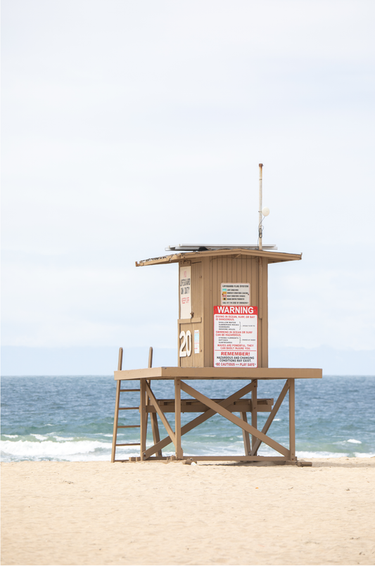 A wide landscape coastal photography view of Newport Beach in Southern California, featuring a lifeguard tower and walls on the beach.