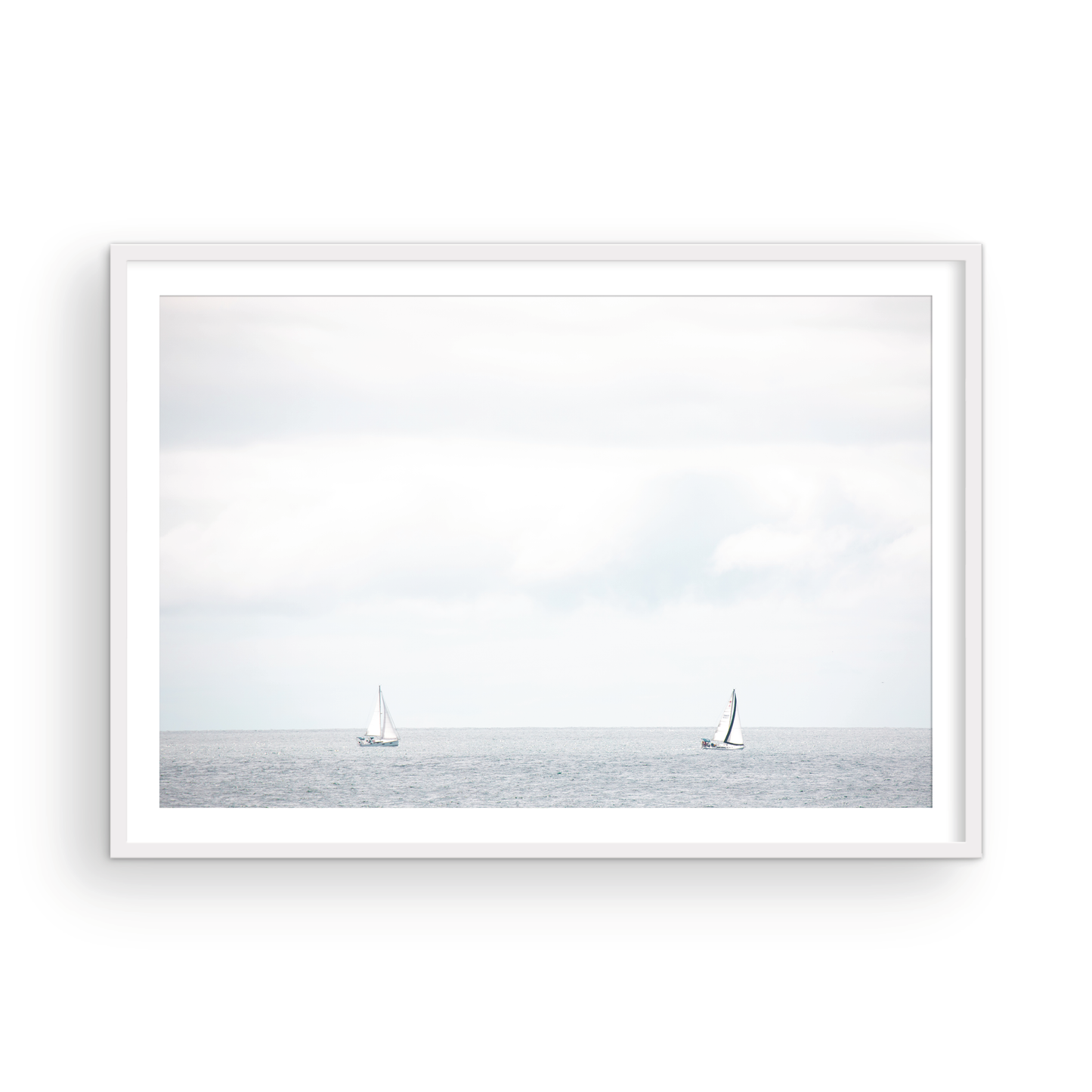 Minimalist ocean print featuring two sailboats on a calm ocean under a vast, bright sky. This serene seascape is ideal for coastal, nautical theme wall art. Photograph in minimalist mock up