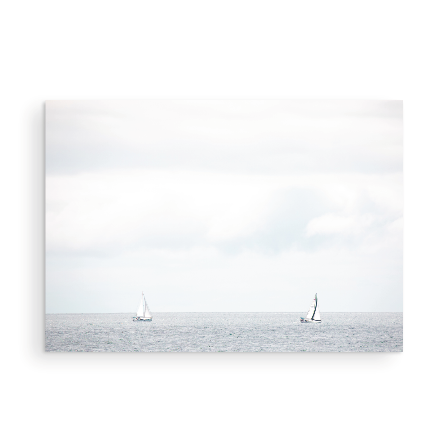 Minimalist ocean print featuring two sailboats on a calm ocean under a vast, bright sky. This serene seascape is ideal for coastal, nautical theme wall art. Photograph in minimalist mock up
