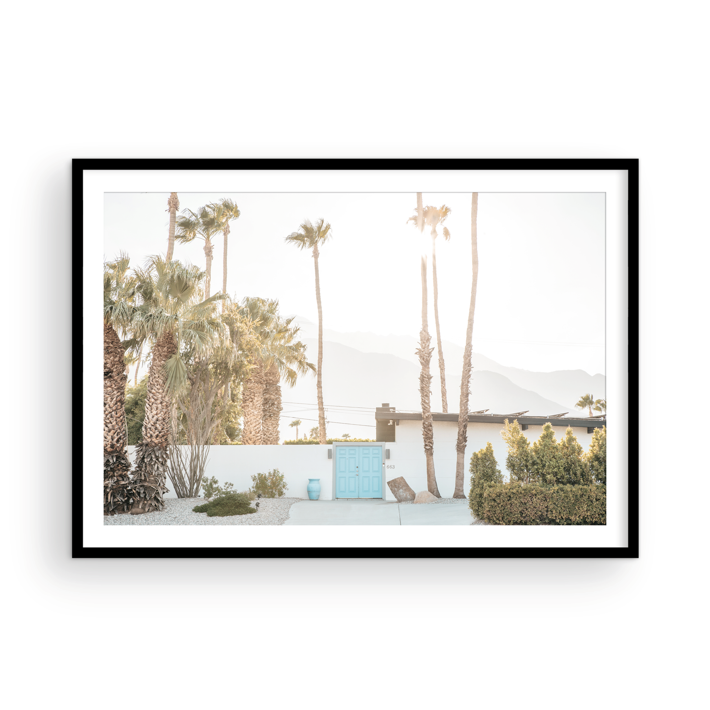 Coastal print of a Palm Springs home with a bright blue door, surrounded by tall palm trees and distant mountains, embodying summer vibes wall art. Photograph in minimalist mock up.