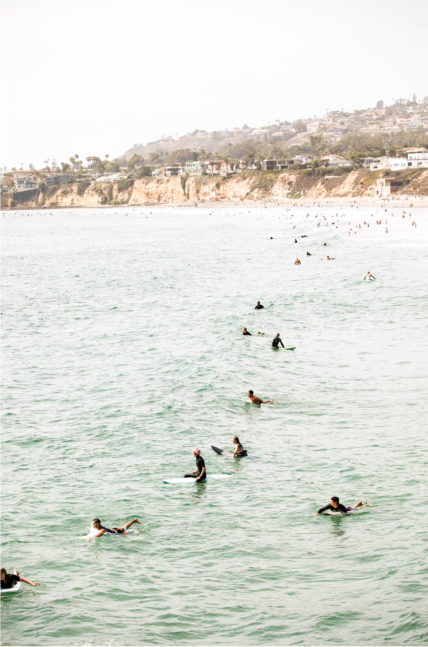 Vertical surf print showing several surfers paddling in the ocean at Pacific Beach, with a distant coastline. This image captures the surfing art of Southern California.