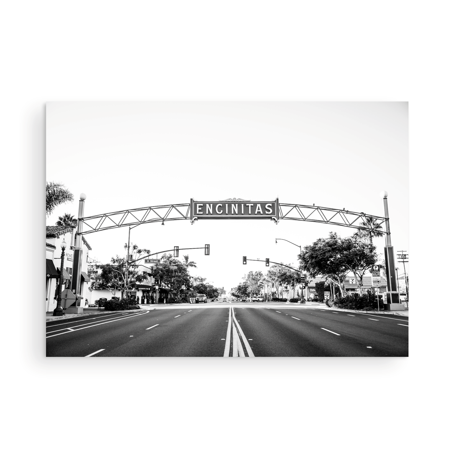 A black and white photograph of a street sign that reads 'Encinitas' with a background of a city street. Photograph in minimalist mock up.