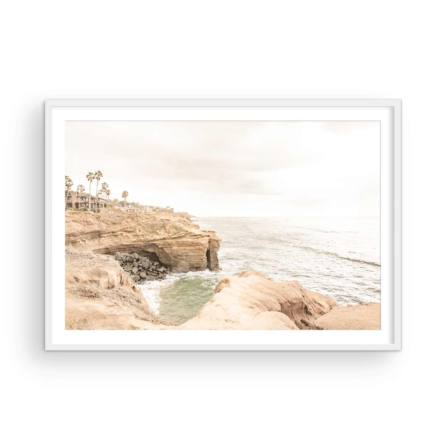 Fine art of Sunset Cliffs, San Diego California horizontal print of hazy high-angle landscape beach photography captures a light blue ocean meeting tall tan, rocky, brown cliffs rise as iconic coastal scenery. Photograph in minimalist mock up.