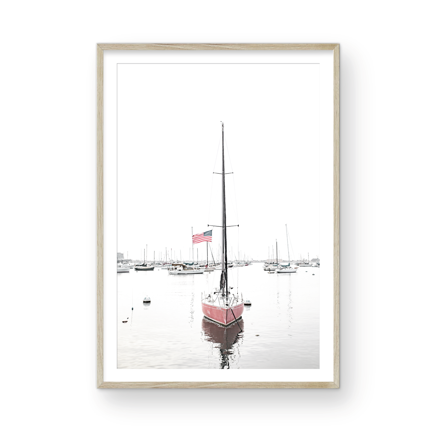 A vertical San Diego print featuring a lone red sailboat with an American flag, anchored in a calm San Diego harbor. This minimalist ocean print captures the essence of coastal photography and is perfect for modern coastal decor. Photograph in minimalist mock up.