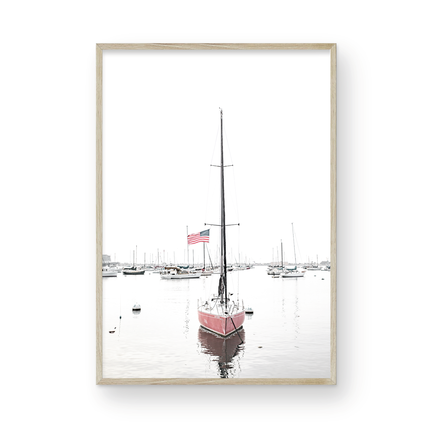 A vertical San Diego print featuring a lone red sailboat with an American flag, anchored in a calm San Diego harbor. This minimalist ocean print captures the essence of coastal photography and is perfect for modern coastal decor. Photograph in minimalist mock up.