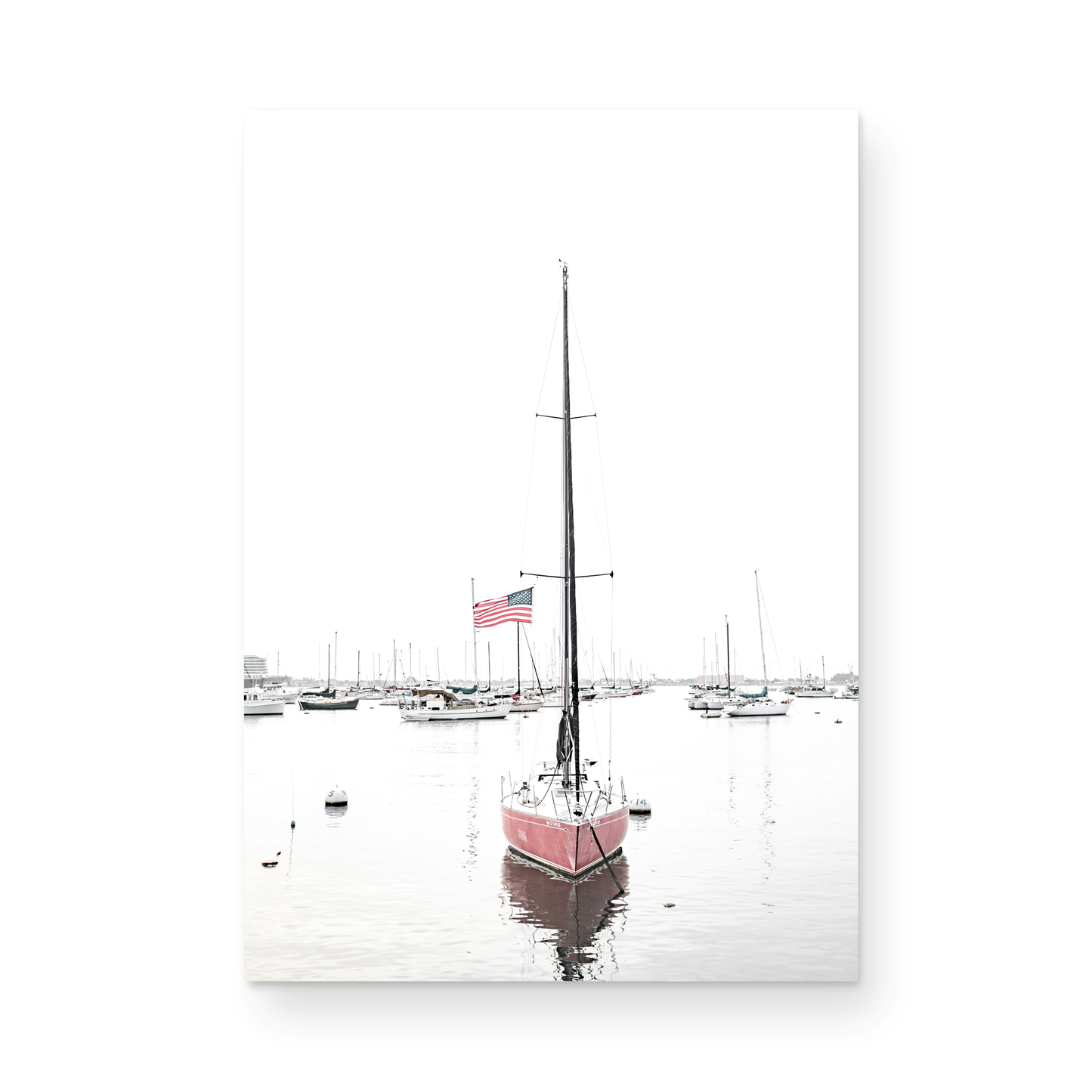 A vertical San Diego print featuring a lone red sailboat with an American flag, anchored in a calm San Diego harbor. This minimalist ocean print captures the essence of coastal photography and is perfect for modern coastal decor. Photograph in minimalist mock up.