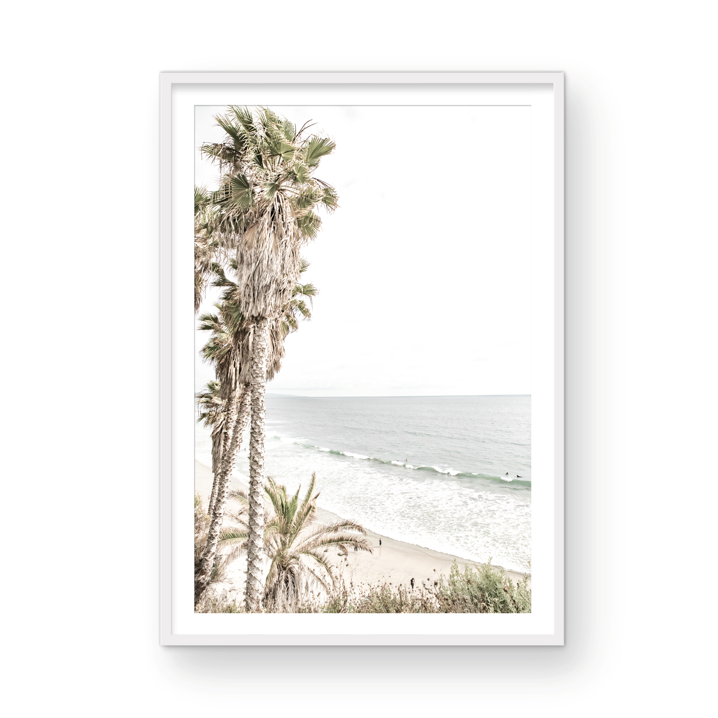 Dreamy coastal palm tree print featuring several tall palm trees with shaggy trunks, lining a gentle slope down to a tranquil beach. This vertical tropical print is captured at Swamis Beach on the Southern California coast, is bathed in bright, hazy sunlight, creating a pastel beach art effect. Evokes serene summer vibes, perfect for beach house decor. Photograph in minimalist surf art mock up.