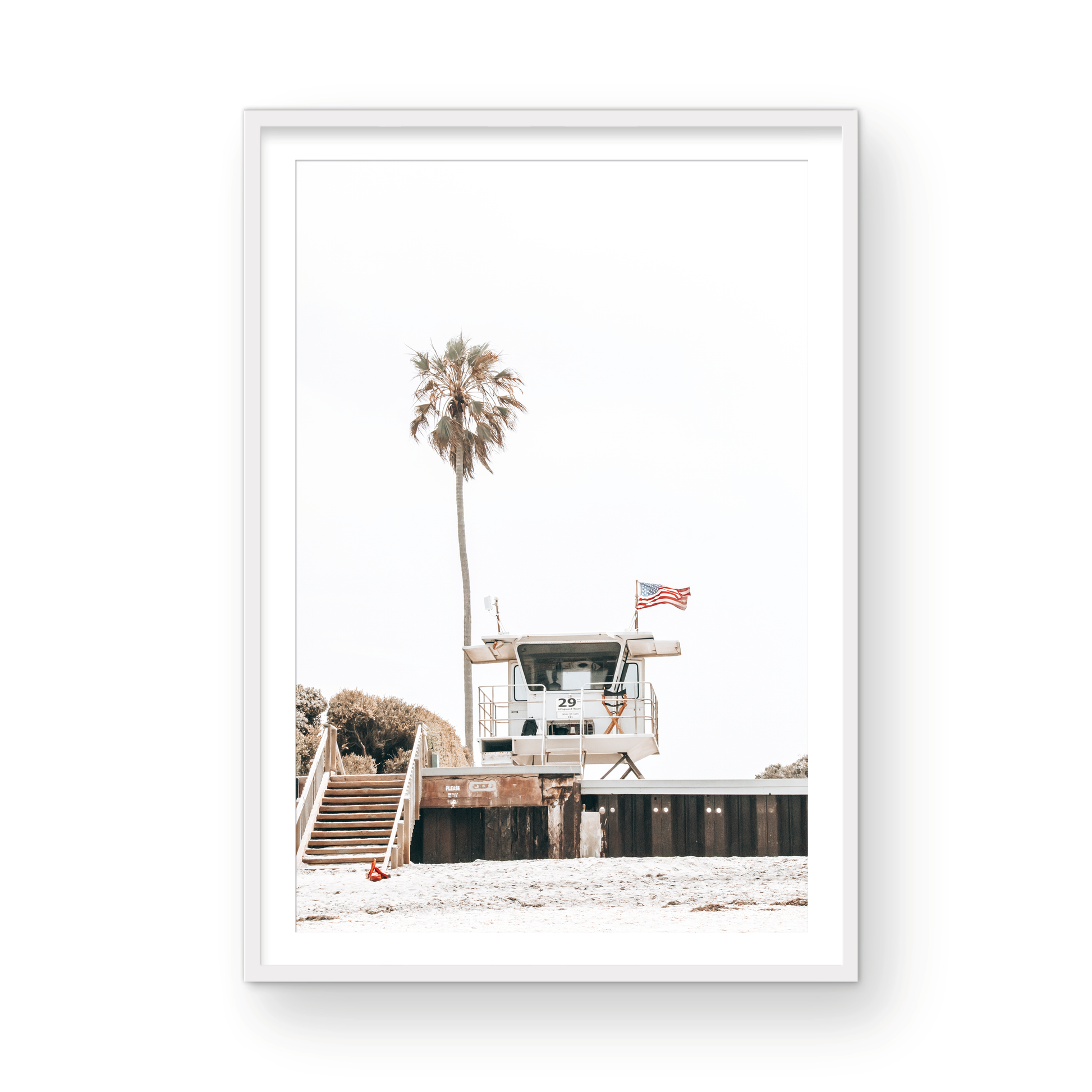 A photograph featuring an American flag on a lifeguard tower with a palm tree in the background, taken at a beach in Del Mar, San Diego. Photograph in minimalist mock up.
