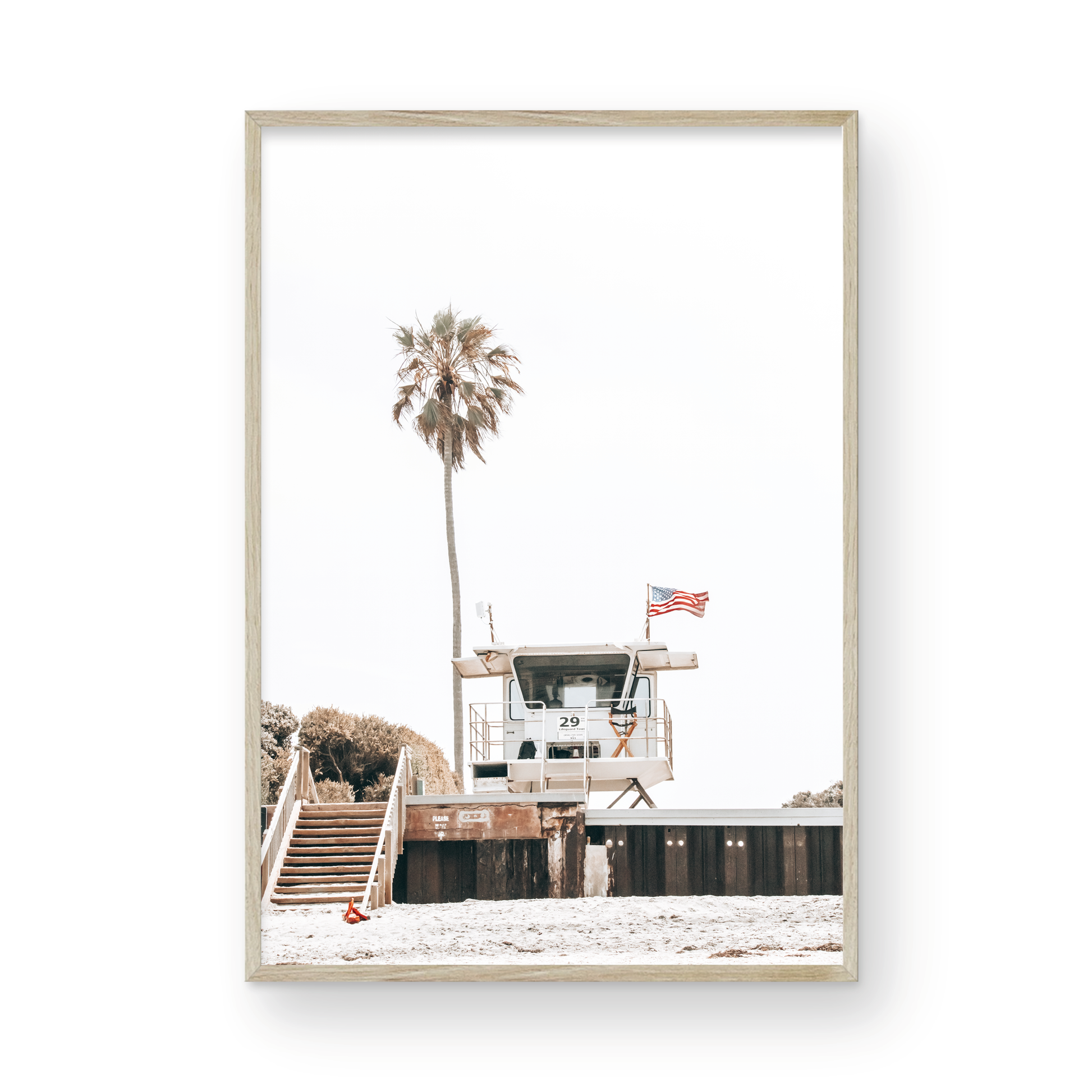 A photograph featuring an American flag on a lifeguard tower with a palm tree in the background, taken at a beach in Del Mar, San Diego. Photograph in minimalist mock up.
