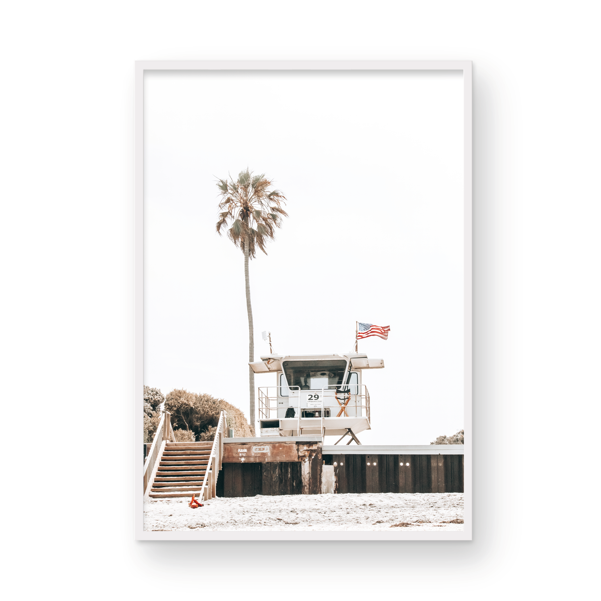 A photograph featuring an American flag on a lifeguard tower with a palm tree in the background, taken at a beach in Del Mar, San Diego. Photograph in minimalist mock up.
