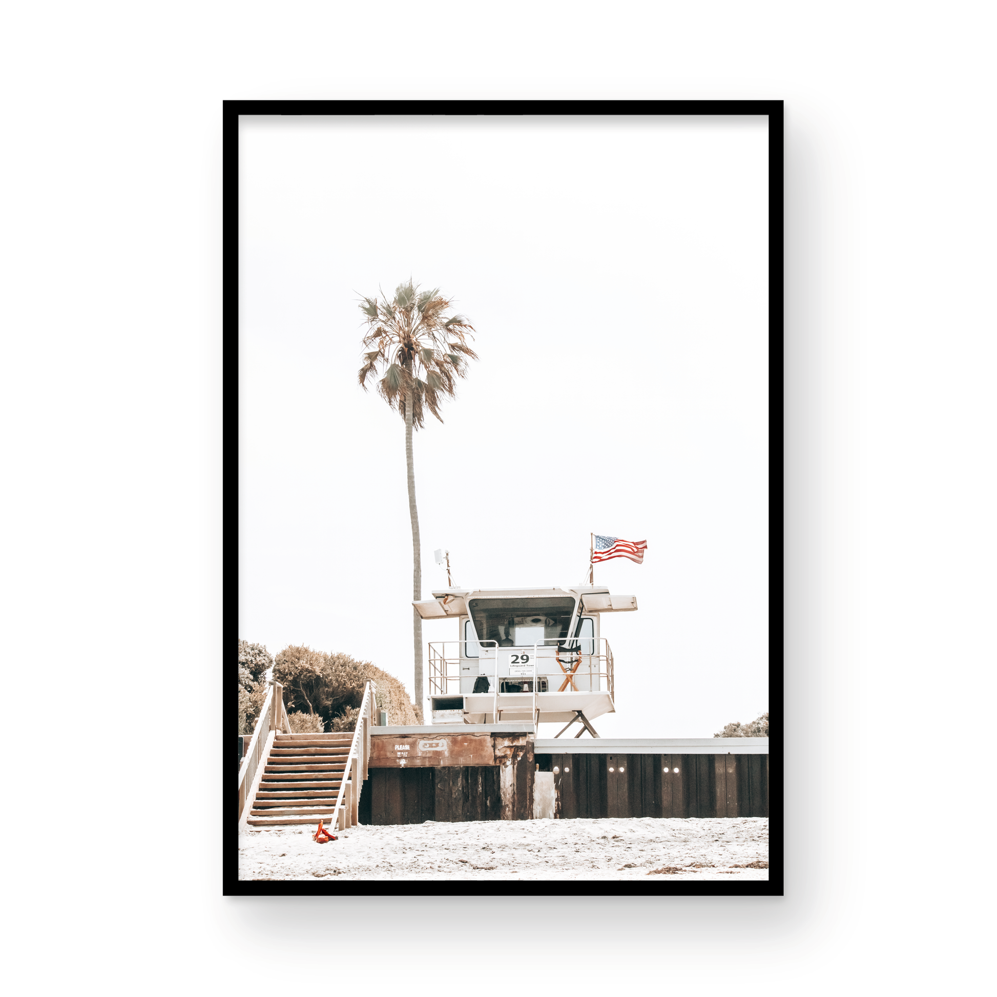 A photograph featuring an American flag on a lifeguard tower with a palm tree in the background, taken at a beach in Del Mar, San Diego. Photograph in minimalist mock up.