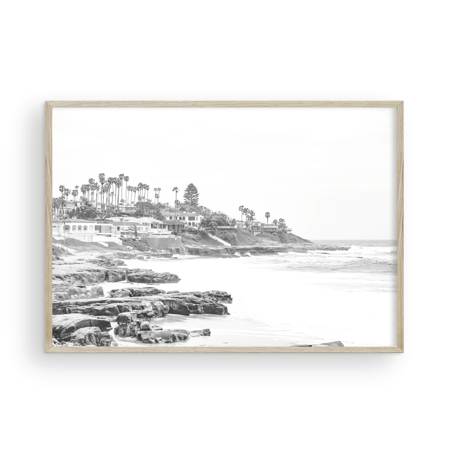 Fine art of WindanSea Beach, La Jolla California horizontal landscape black and white print by Southern California photographer Kim Dybczak of Salt Creek Prints, featuring a powerful waves crashing against the rocky shore of California coast. Beach homes and palm trees sit atop the cliffside, with stairs leading down to a sheltered area. Photograph in minimalist framed mock up