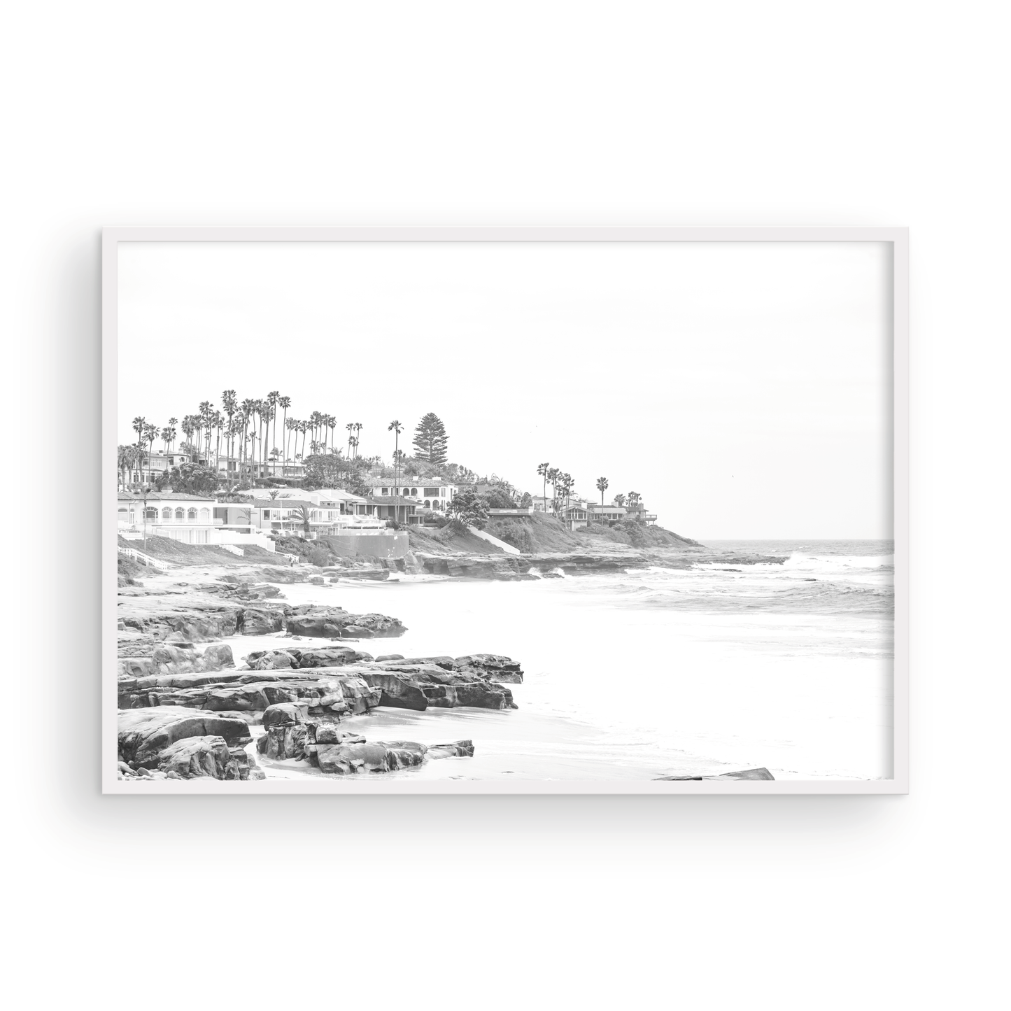 Fine art of WindanSea Beach, La Jolla California horizontal landscape black and white print by Southern California photographer Kim Dybczak of Salt Creek Prints, featuring a powerful waves crashing against the rocky shore of California coast. Beach homes and palm trees sit atop the cliffside, with stairs leading down to a sheltered area. Photograph in minimalist framed mock up