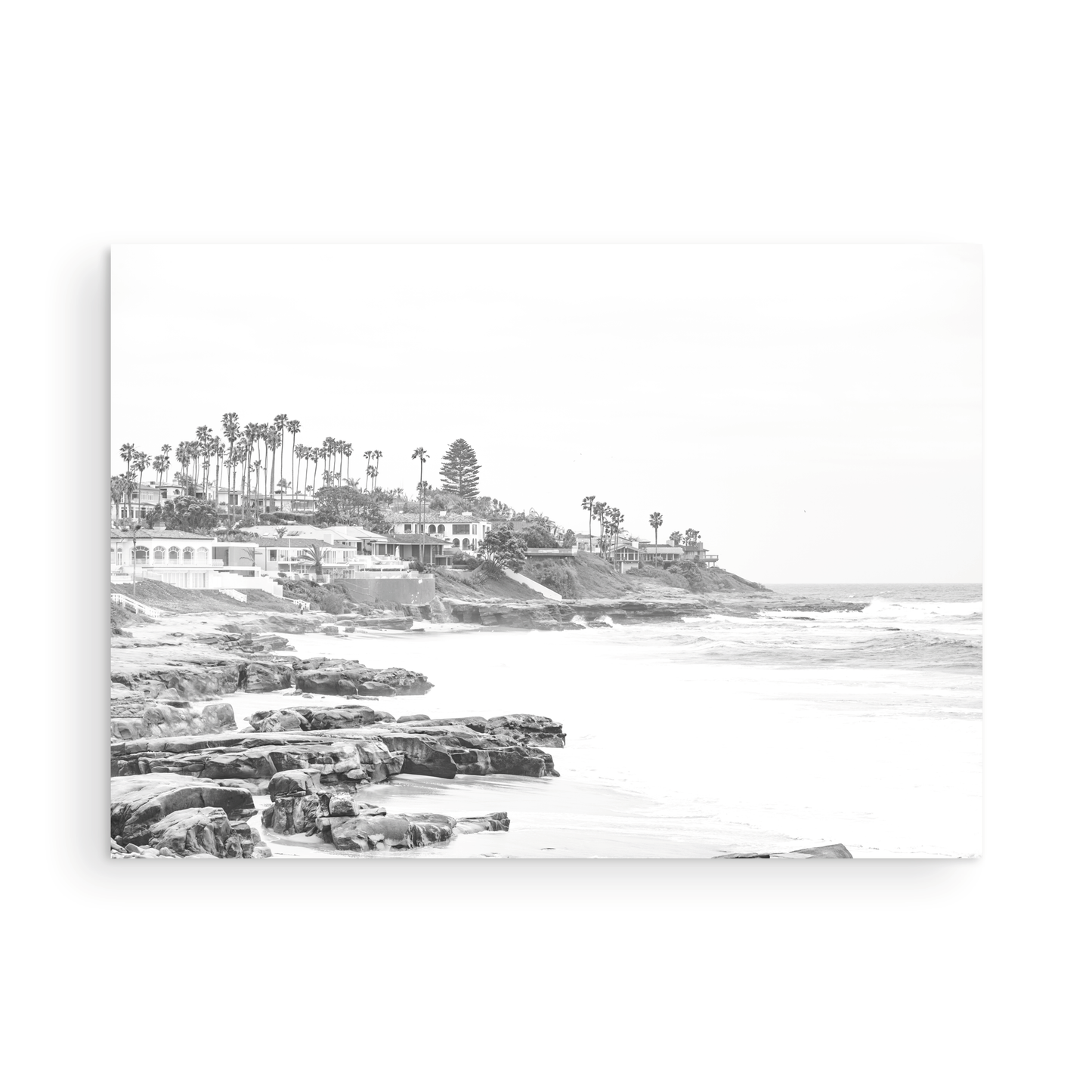Fine art of WindanSea Beach, La Jolla California horizontal landscape black and white print by Southern California photographer Kim Dybczak of Salt Creek Prints, featuring a powerful waves crashing against the rocky shore of California coast. Beach homes and palm trees sit atop the cliffside, with stairs leading down to a sheltered area. Photograph in minimalist framed mock up