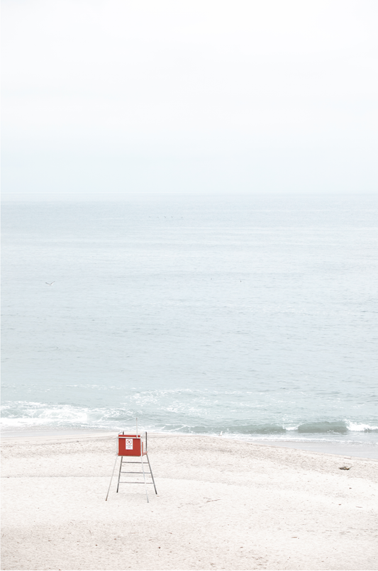 Vertical coastal photography featuring a red and white lifeguard chair and a calm ocean background, located in Laguna California.