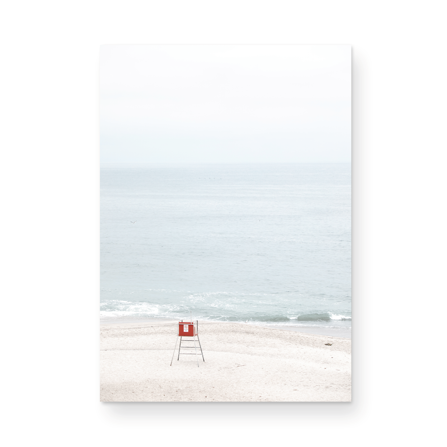 Vertical coastal photography featuring a red and white lifeguard chair and a calm ocean background, located in Laguna California. Photograph in minimalist mock up.