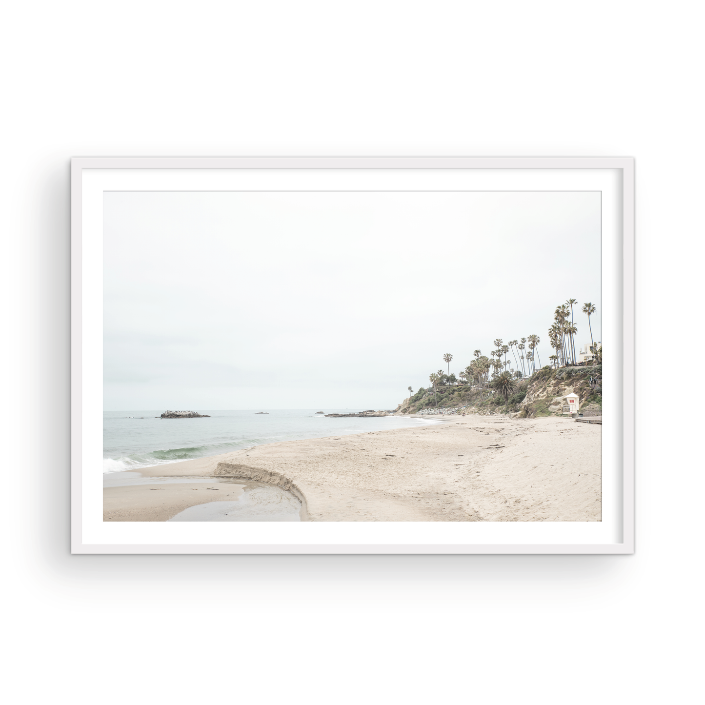 Horizontal coastal photography of a white lifeguard tower at Laguna Beach, California, depicting a beach scene with palm trees and a calm ocean. Photograph in minimalist mock up.