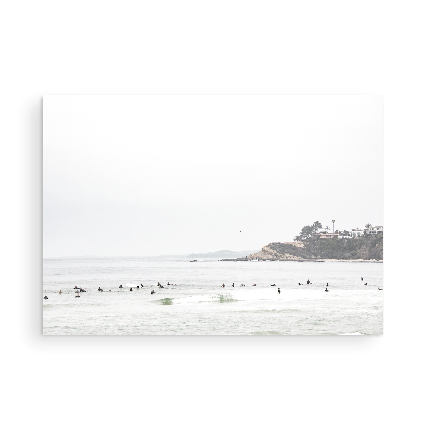 Landscape surf wall decor showing many surfers waiting for waves in the ocean at Salt Creek Beach, with a distant cliffside. This print captures the surf vibes of Southern California. Photograph in minimalist mock up.
