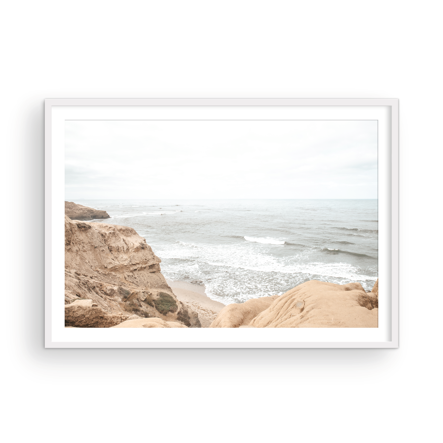 Fine art of Sunset Cliffs, San Diego California horizontal print of hazy high-angle landscape beach photography captures a light blue ocean meeting tall tan and brown cliffs rise as iconic coastal scenery. Photograph in minimalist mock up.