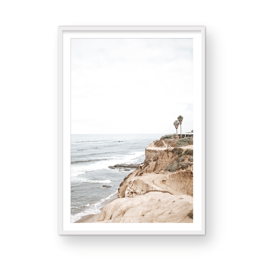 Fine art of Sunset Cliffs, San Diego California vertical print of hazy high-angle landscape beach photography captures a light blue ocean meeting tall tan and brown cliffs rise as iconic coastal scenery. Photograph in minimalist mock up.