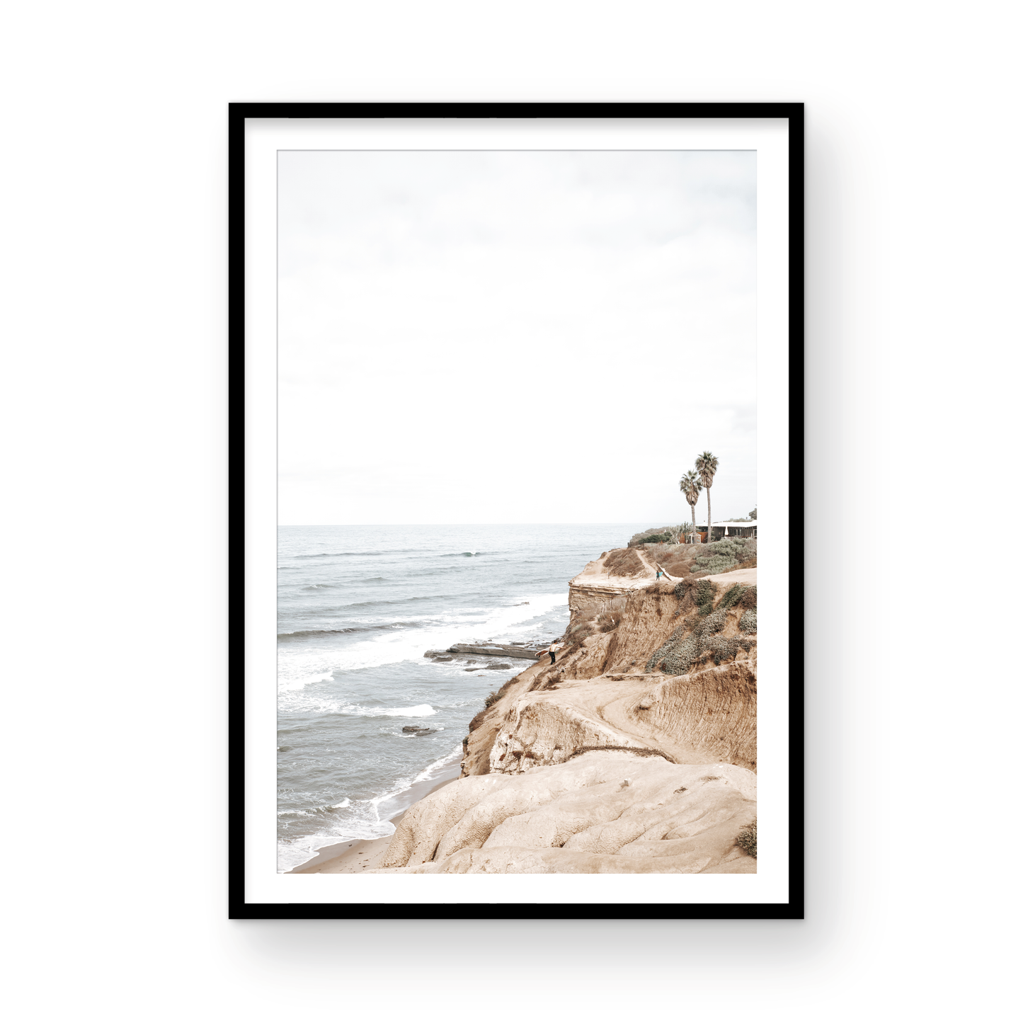 Fine art of Sunset Cliffs, San Diego California vertical print of hazy high-angle landscape beach photography captures a light blue ocean meeting tall tan and brown cliffs rise as iconic coastal scenery. Photograph in minimalist mock up.