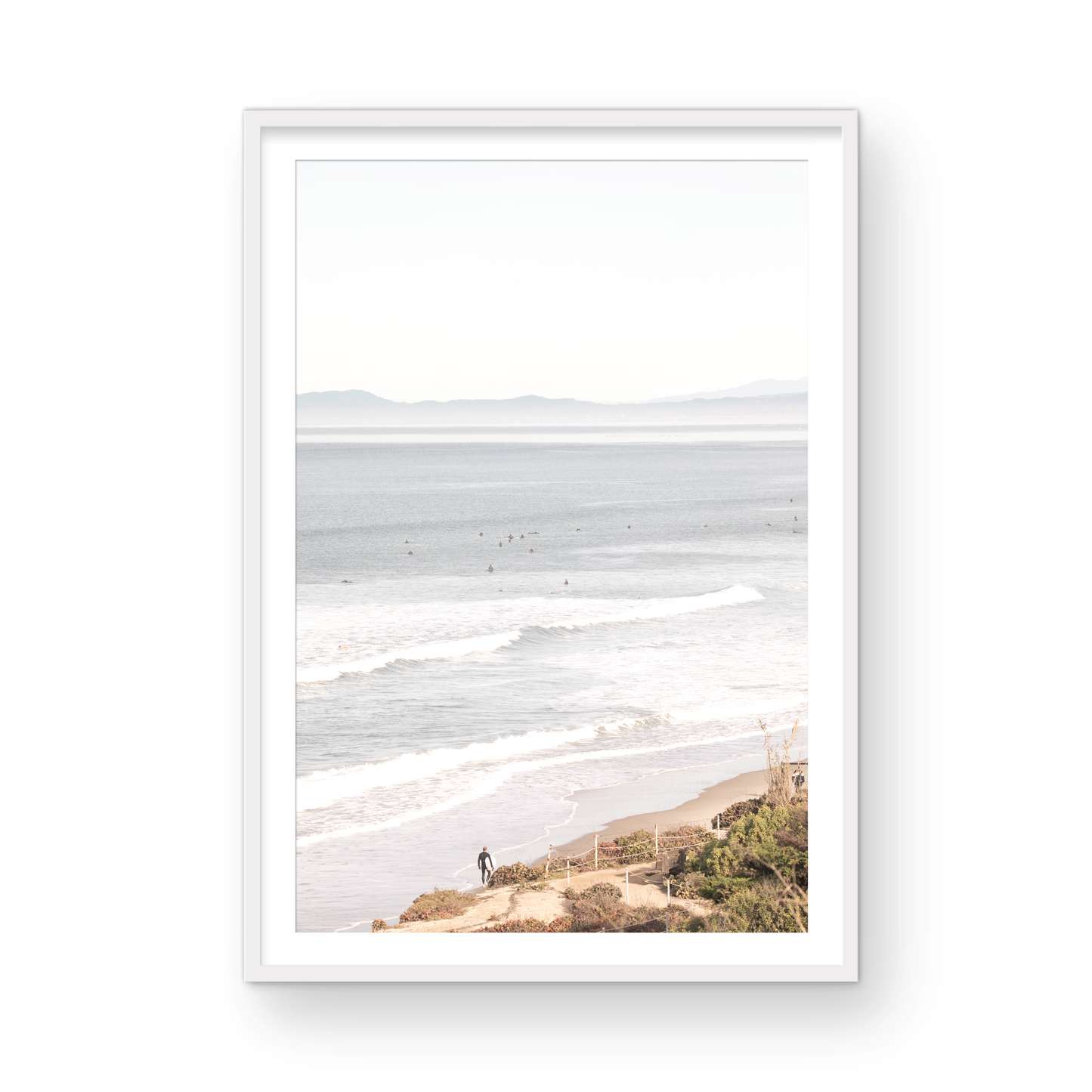 Minimalist ocean print of ocean waves with surfers in the distance and a sandy hillside in the foreground. Photograph in minimalist mock up.