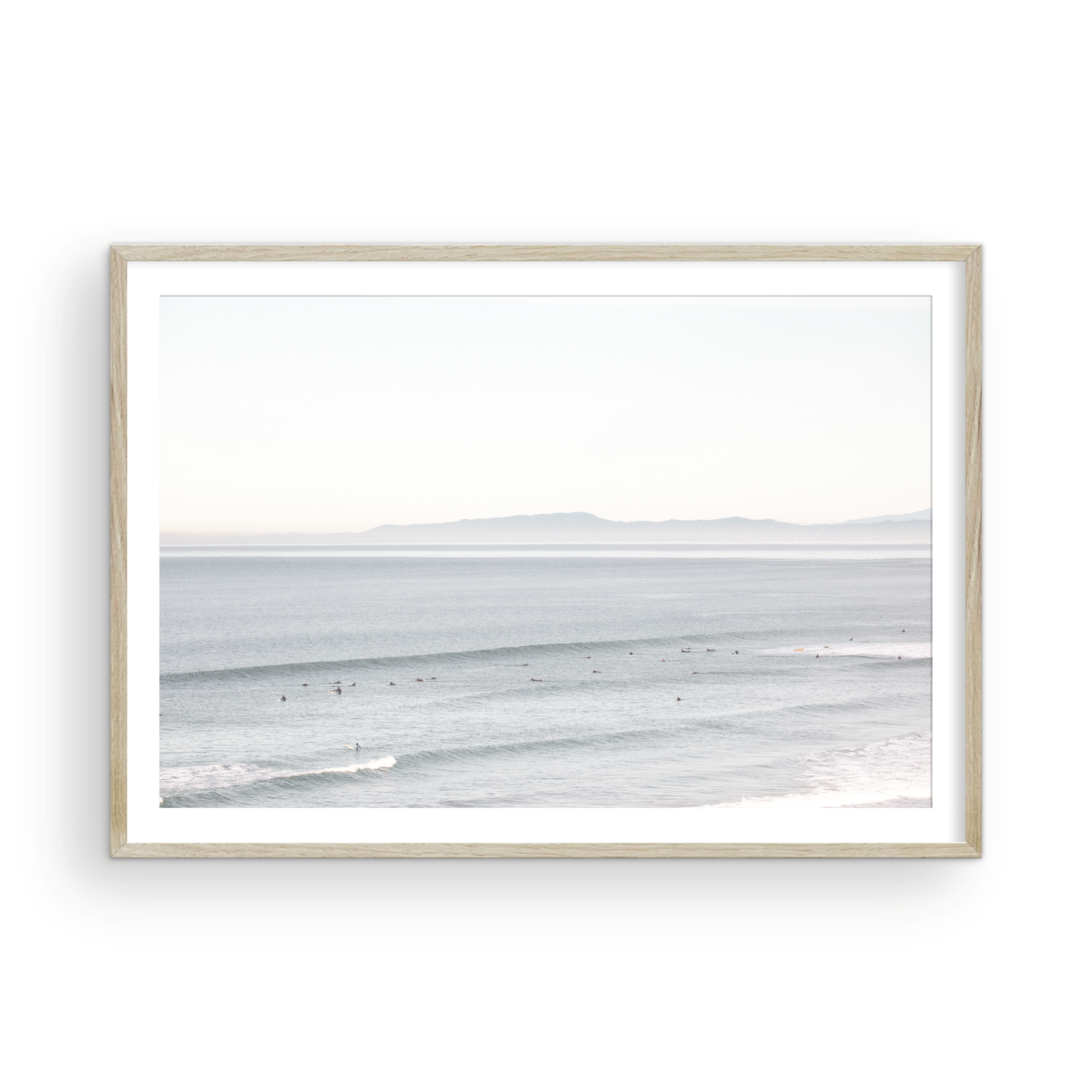 Coastal photography featuring a calm ocean scene with gentle waves and a hazy horizon line, predominantly in blue and white tones. Photograph in minimalist mock up.