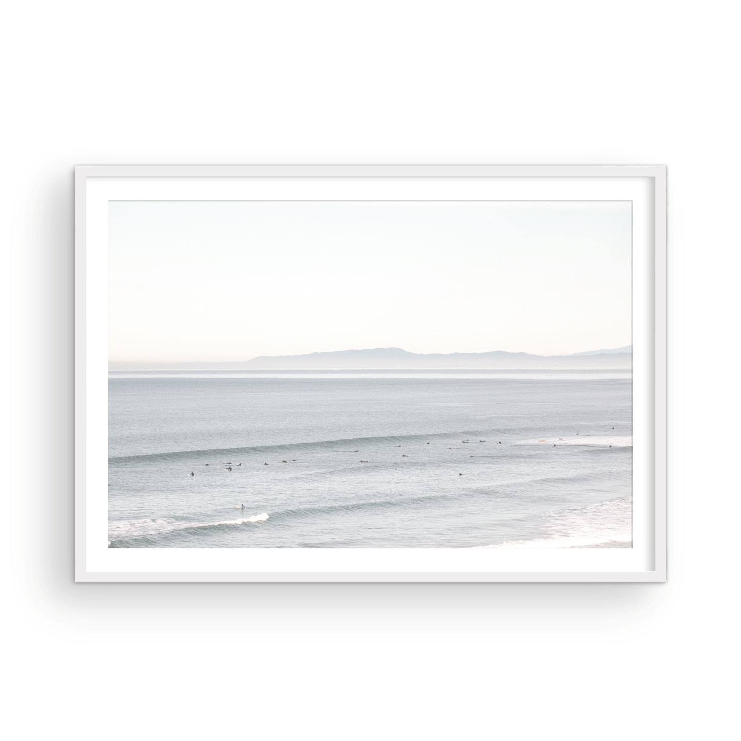 Coastal photography featuring a calm ocean scene with gentle waves and a hazy horizon line, predominantly in blue and white tones. Photograph in minimalist mock up.