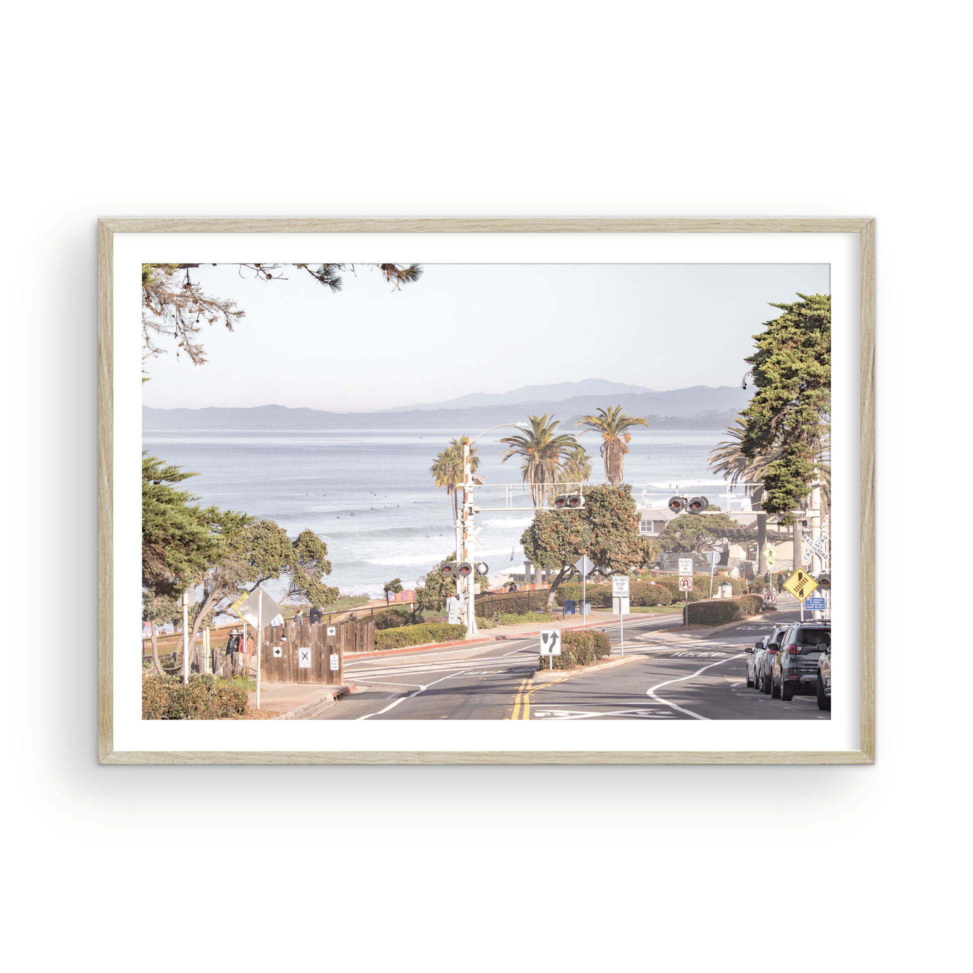 Coastal fine art photography print featuring a scenic view of a coastal road with palm trees, ocean in the background. Photograph in minimalist mock up.