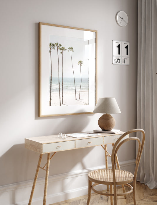 Vertical coastal print showcasing a line of very tall palm trees against the bright sky, overlooking the calm ocean waves. A quintessential tropical coastal print. Photograph in minimalist mock up.