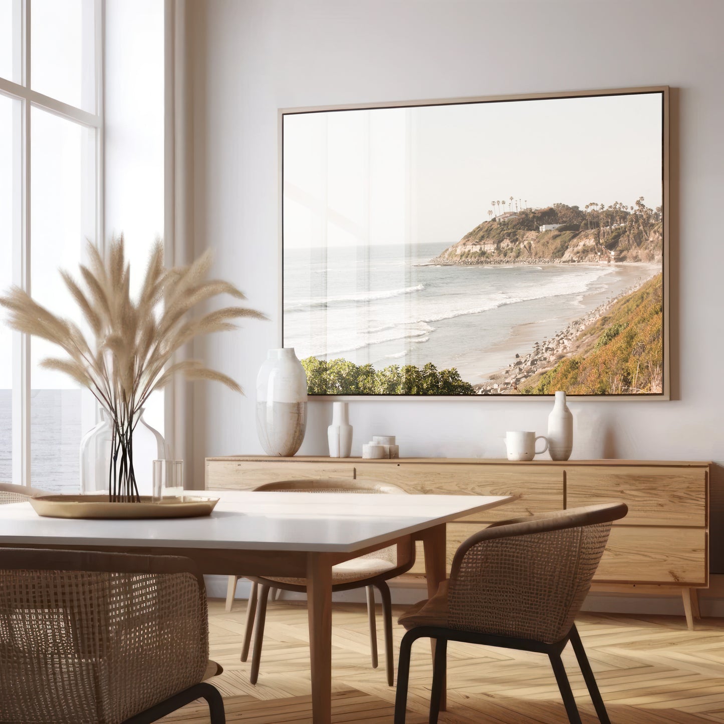 Fine art of Swamis Beach, San Diego California horizontal print of hazy high-angle landscape beach photography captures a light blue ocean meeting a sandy beach with many beach goers. To the right, tall tan and brown cliffs rise as iconic coastal scenery. Photograph in minimalist framed mock up.
