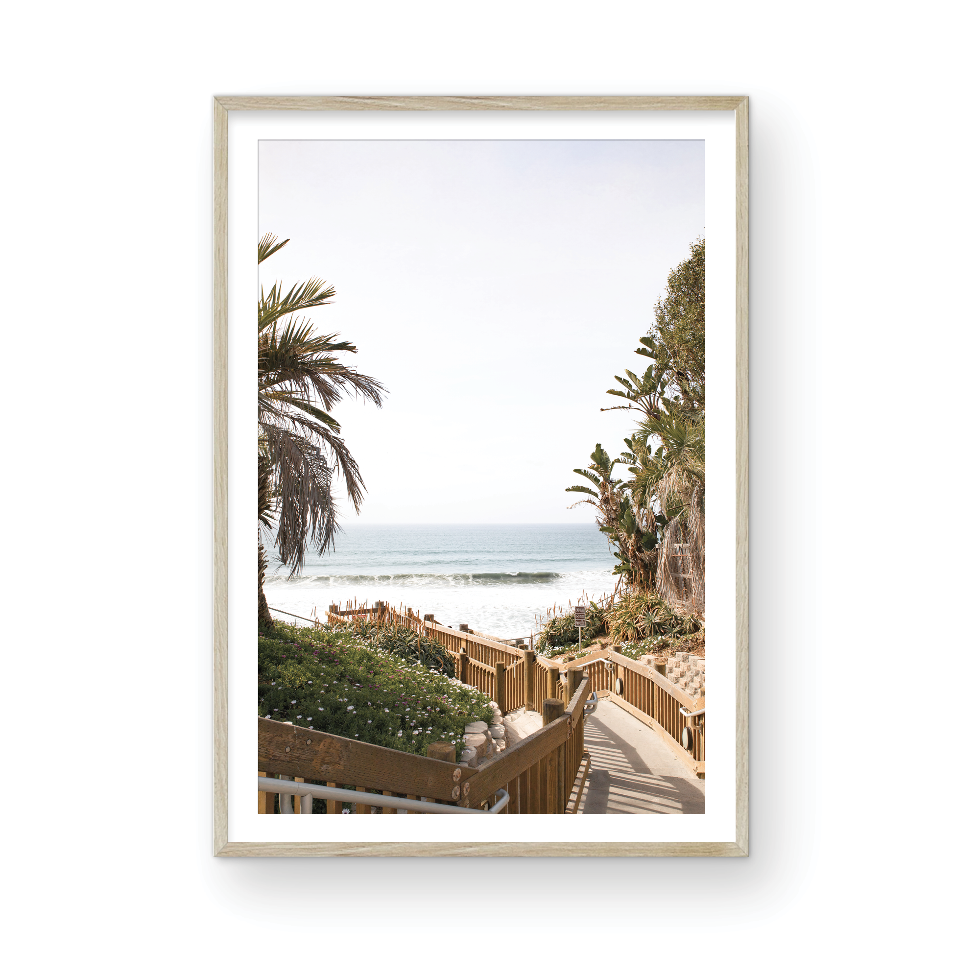 Vertical coastal wall print featuring a stairway leading down to a beach with palm trees and ocean view. Photograph in minimalist mock up.