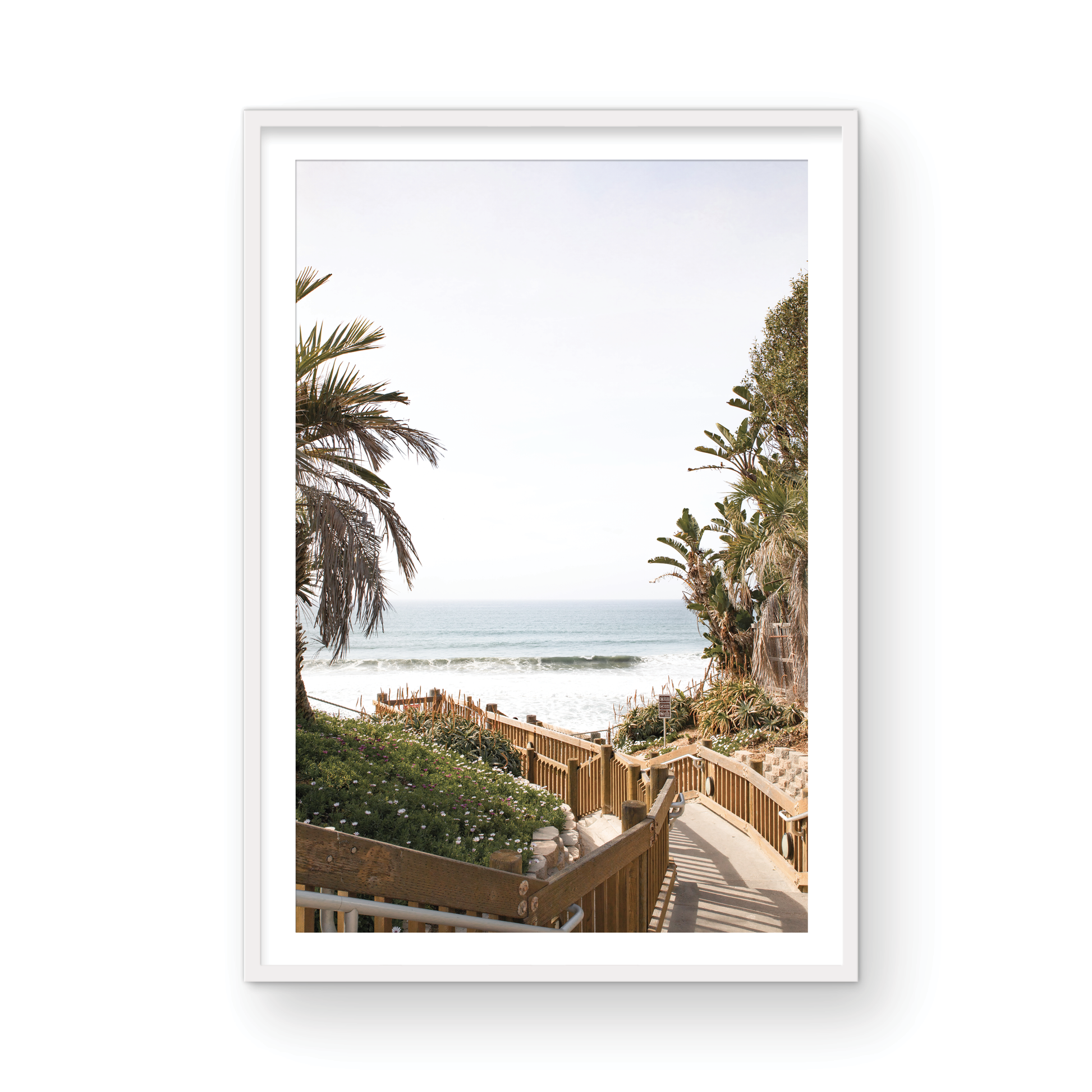 Vertical coastal wall print featuring a stairway leading down to a beach with palm trees and ocean view. Photograph in minimalist mock up.