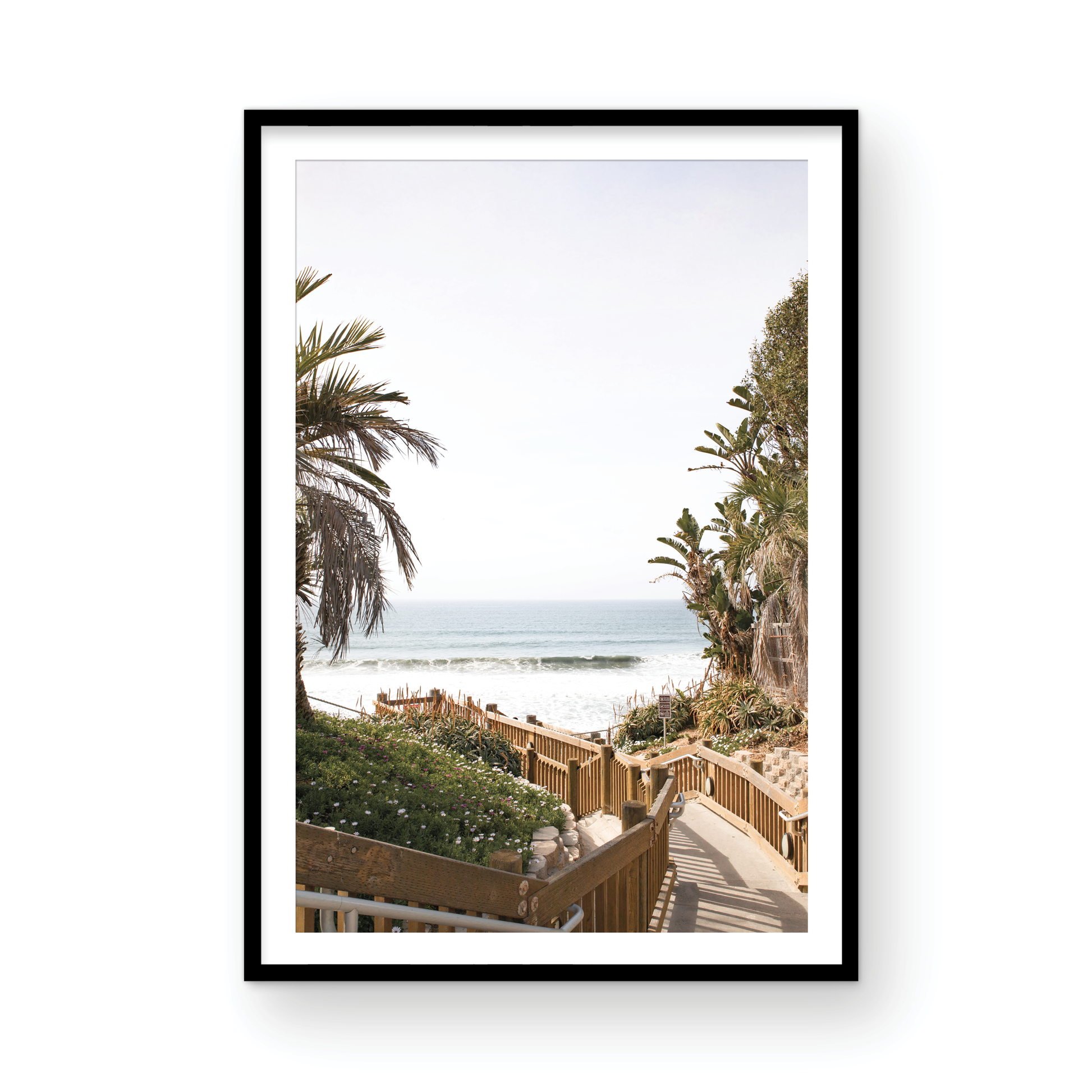 Vertical coastal wall print featuring a stairway leading down to a beach with palm trees and ocean view. Photograph in minimalist mock up.