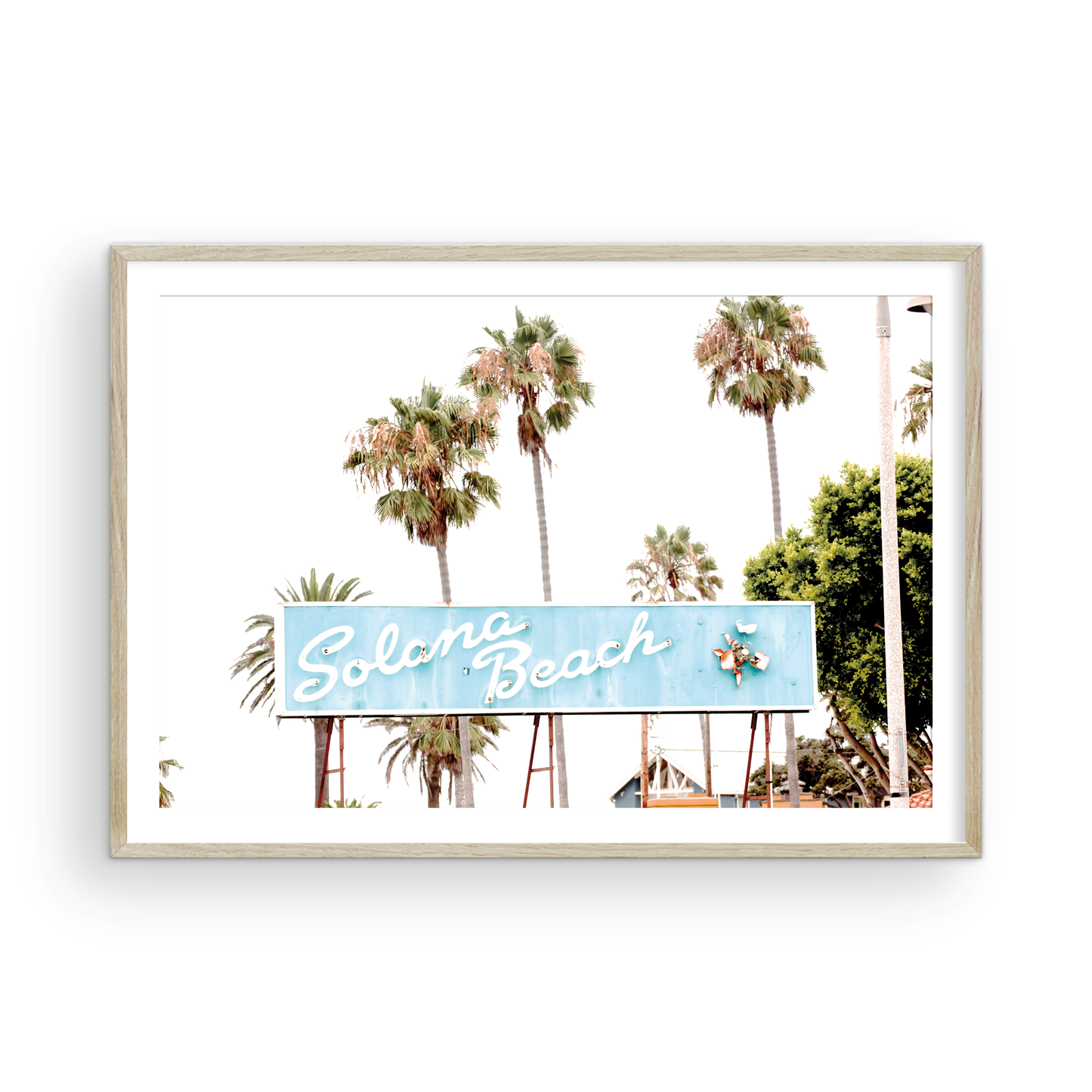 Colorful travel photography capturing the iconic 'Solana Beach' sign, a quintessential piece of Surf Signs San Diego art. The retro light blue sign, adorned with white cursive script and a unique steer head logo, is set against a backdrop of towering palm trees and a bright, hazy California sky. This Southern California surf beach sign evokes strong summer vibes and is perfect for coastal decor. Photograph in minimalist framed mock up.