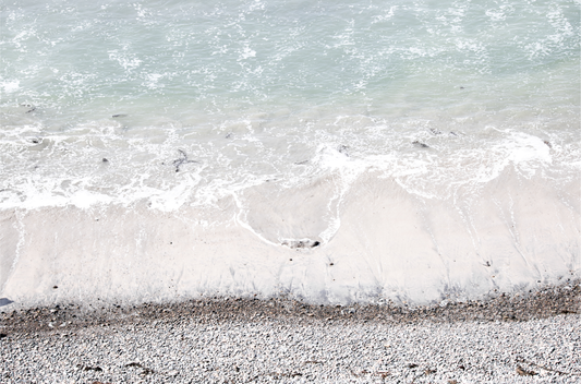 Horizontal surf print of a rocky beach next to foamy ocean waves. This surfing art captures a unique coastline.