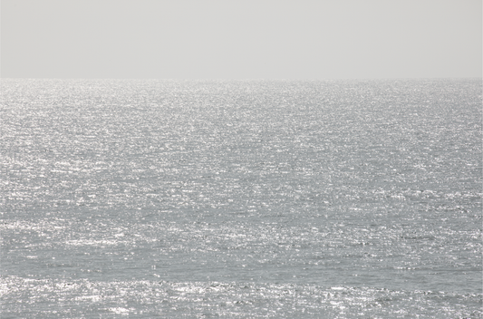 Minimalist ocean art print of a bright, sunlit ocean surface, creating a sparkling seascape. This calm ocean print is perfect for modern coastal decor.