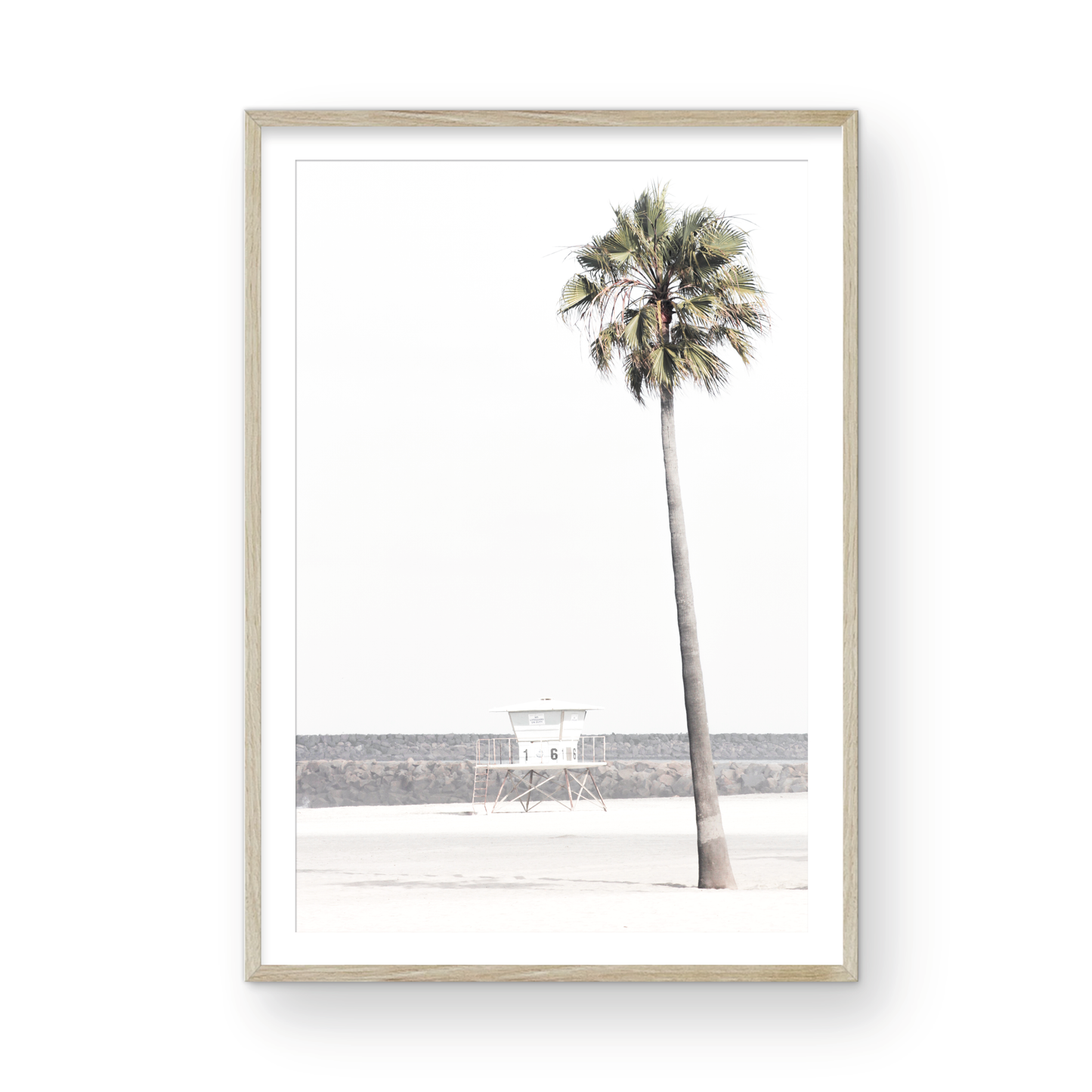Dreamy coastal palm tree print featuring a tall palm tree in the foreground and a pastel blue lifeguard tower centered in the distance. This vertical tropical print is captured at Oceanside Beach on the Southern California coast, is bathed in bright, hazy sunlight, creating a pastel beach art effect. Photograph in minimalist mock up.
